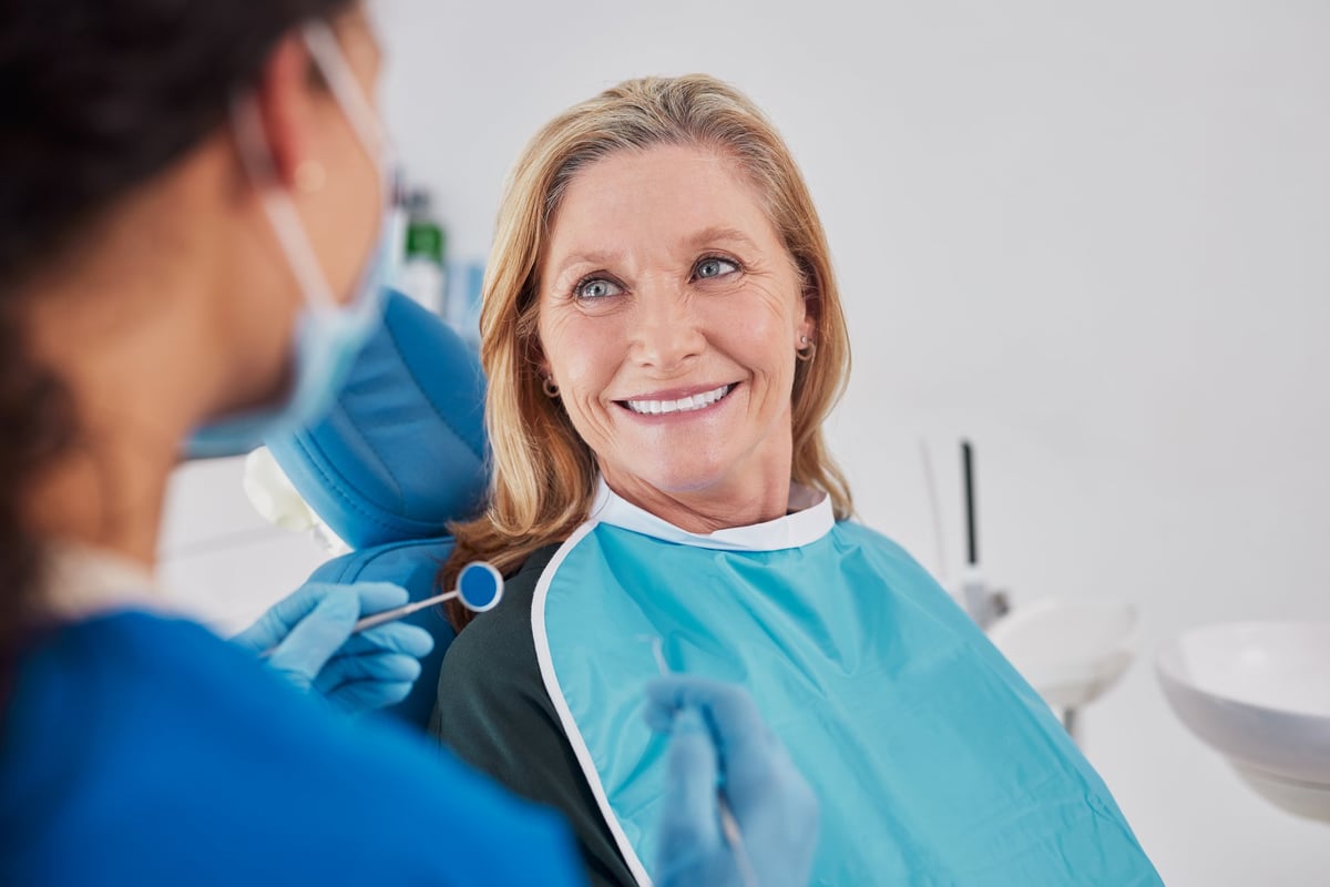 Older woman smiling while looking at dentist during examination in modern private clinic.